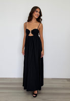 Woman wearing a black evening gown with cut-out design against a plain background