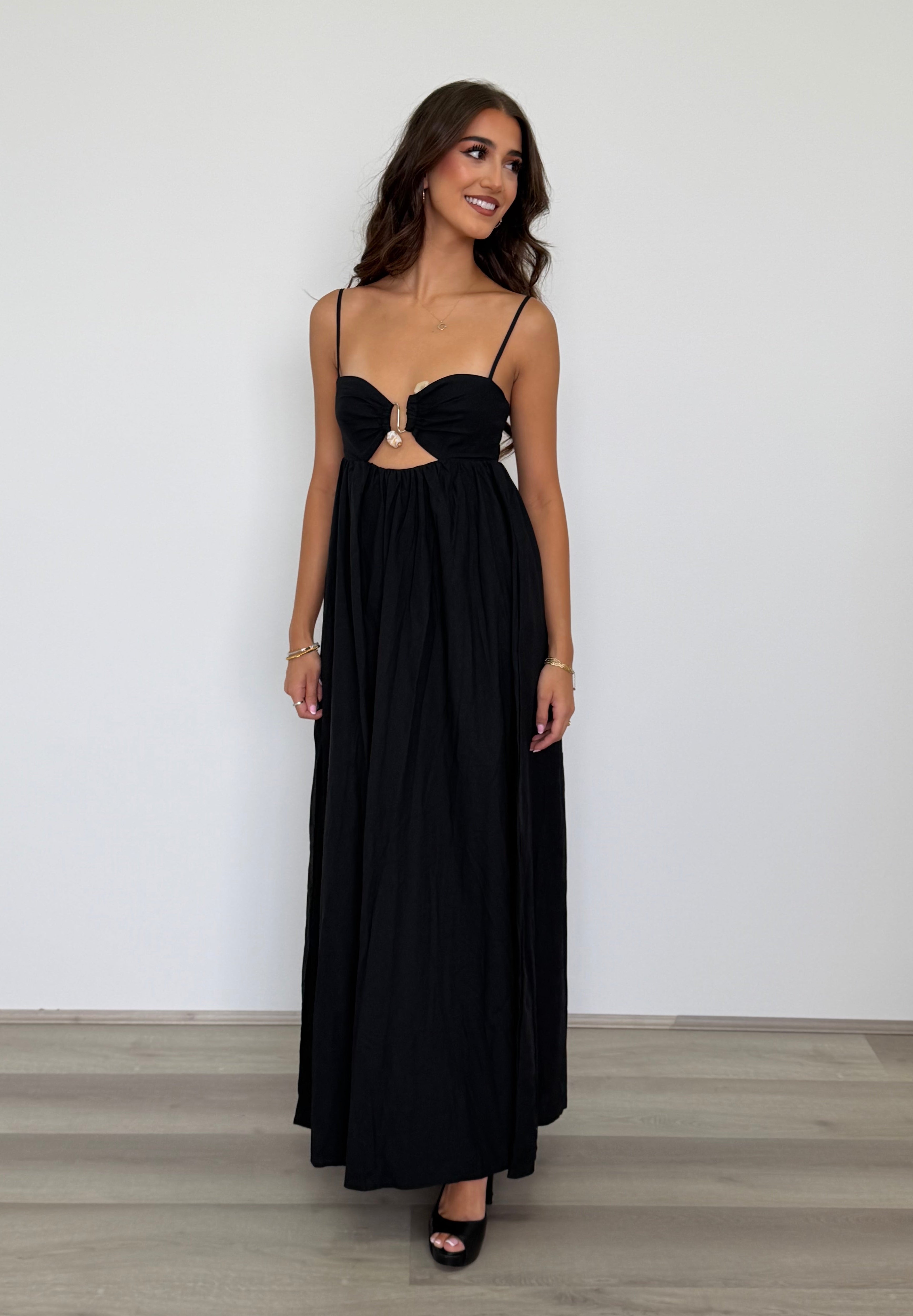 Woman wearing a black evening gown with cut-out design against a plain background