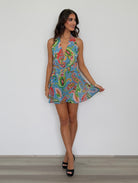 Woman wearing a colorful patterned dress against a plain background