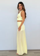 Woman wearing a light yellow two-piece outfit against a white background