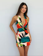 Woman wearing a colorful geometric-patterned dress against a plain background