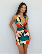 Woman wearing a colorful geometric-patterned dress against a plain background